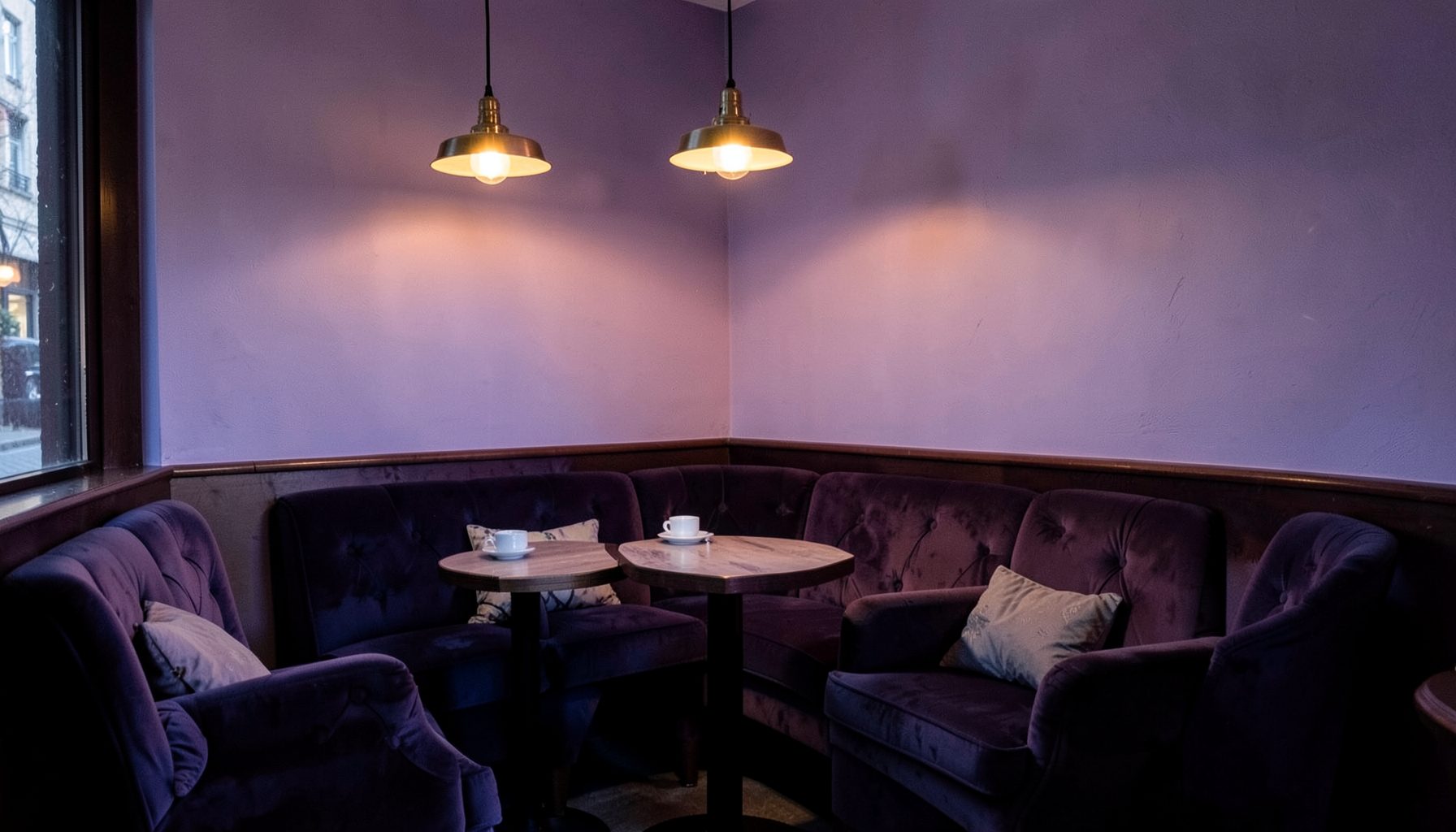 A cozy bistro corner with plush seating, warm pendant lighting, and a soft violet-to-indigo color wash across the walls, evoking relaxed European dining